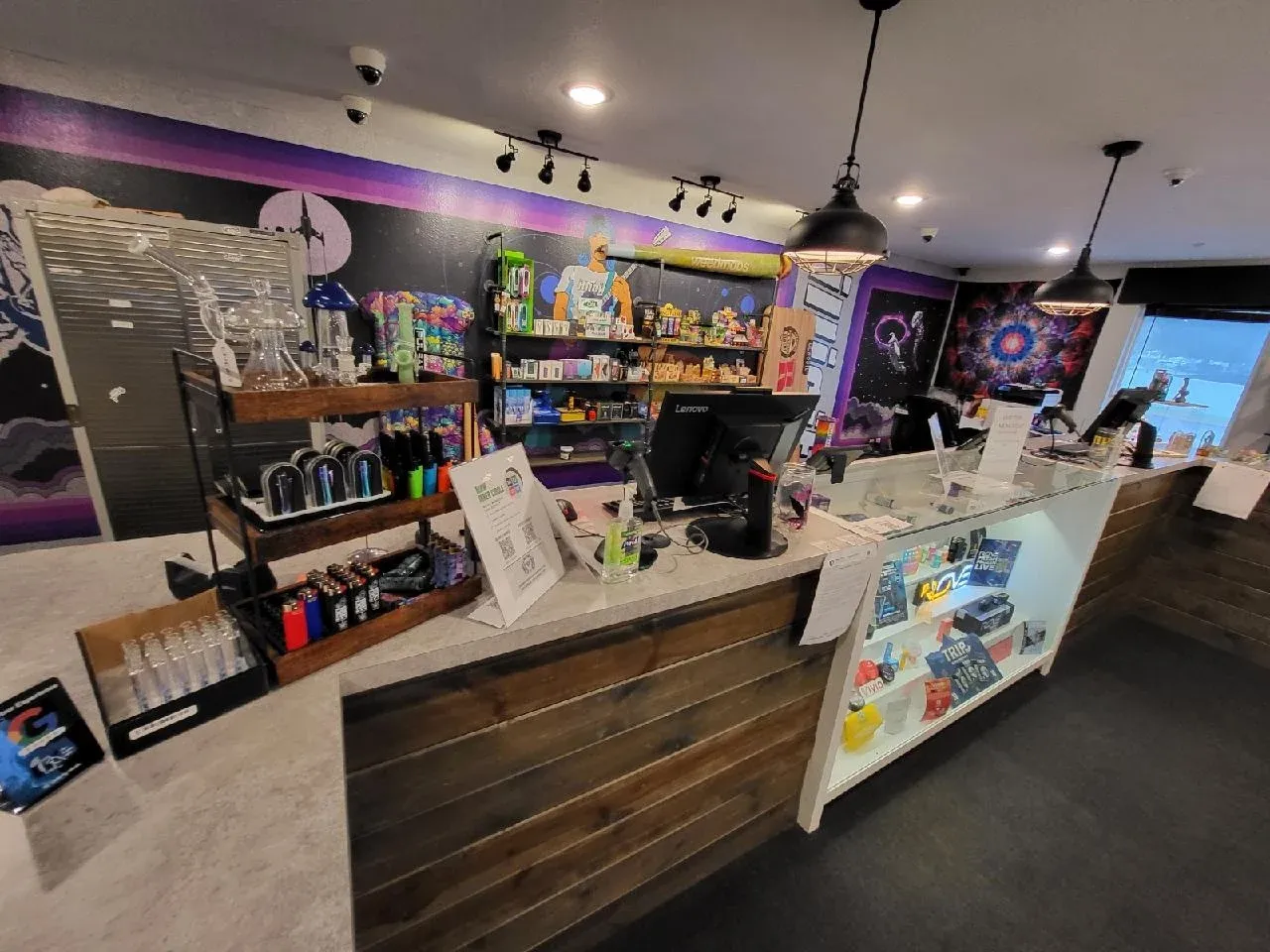 # Alt Text

Interior view of cannabis dispensary with wooden counter, shelving, and purple ambient lighting